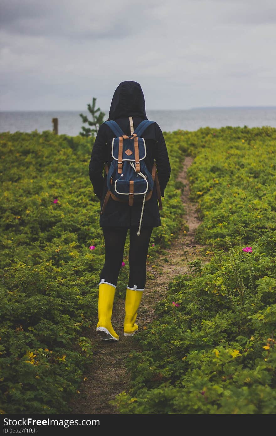 A backpacker in the wild walking on a path with yellow rubber boots. A backpacker in the wild walking on a path with yellow rubber boots.