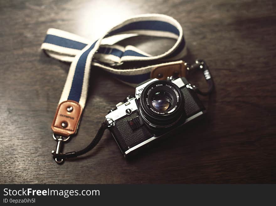 Vintage Olympus analog film camera with strap on wooden table. Vintage Olympus analog film camera with strap on wooden table.