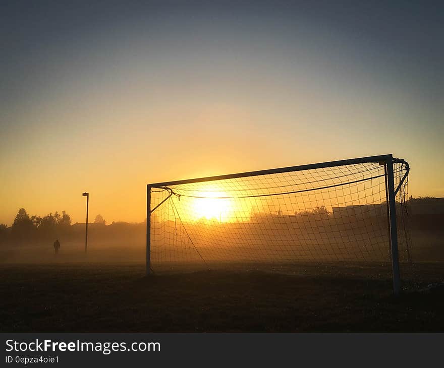 Person Jogging Near Soccer Goal during Sunrise