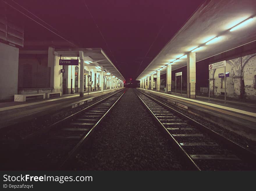 Track leading past empty railroad platform station illuminated at night. Track leading past empty railroad platform station illuminated at night.