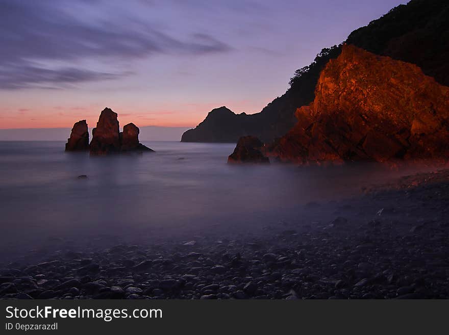 Tall Rock Formation Submerged in Water Near the Shore during Golden Hour