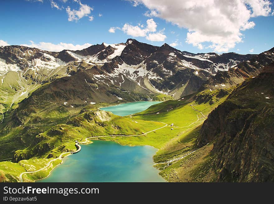 Aerial view over road around alpine lakes with mountain peaks against blue skies in Turin, Italy. Aerial view over road around alpine lakes with mountain peaks against blue skies in Turin, Italy.