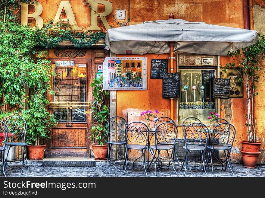 Black Wrought Metal Armless Chairs Outside Bar Under White Patio Table during Daytime