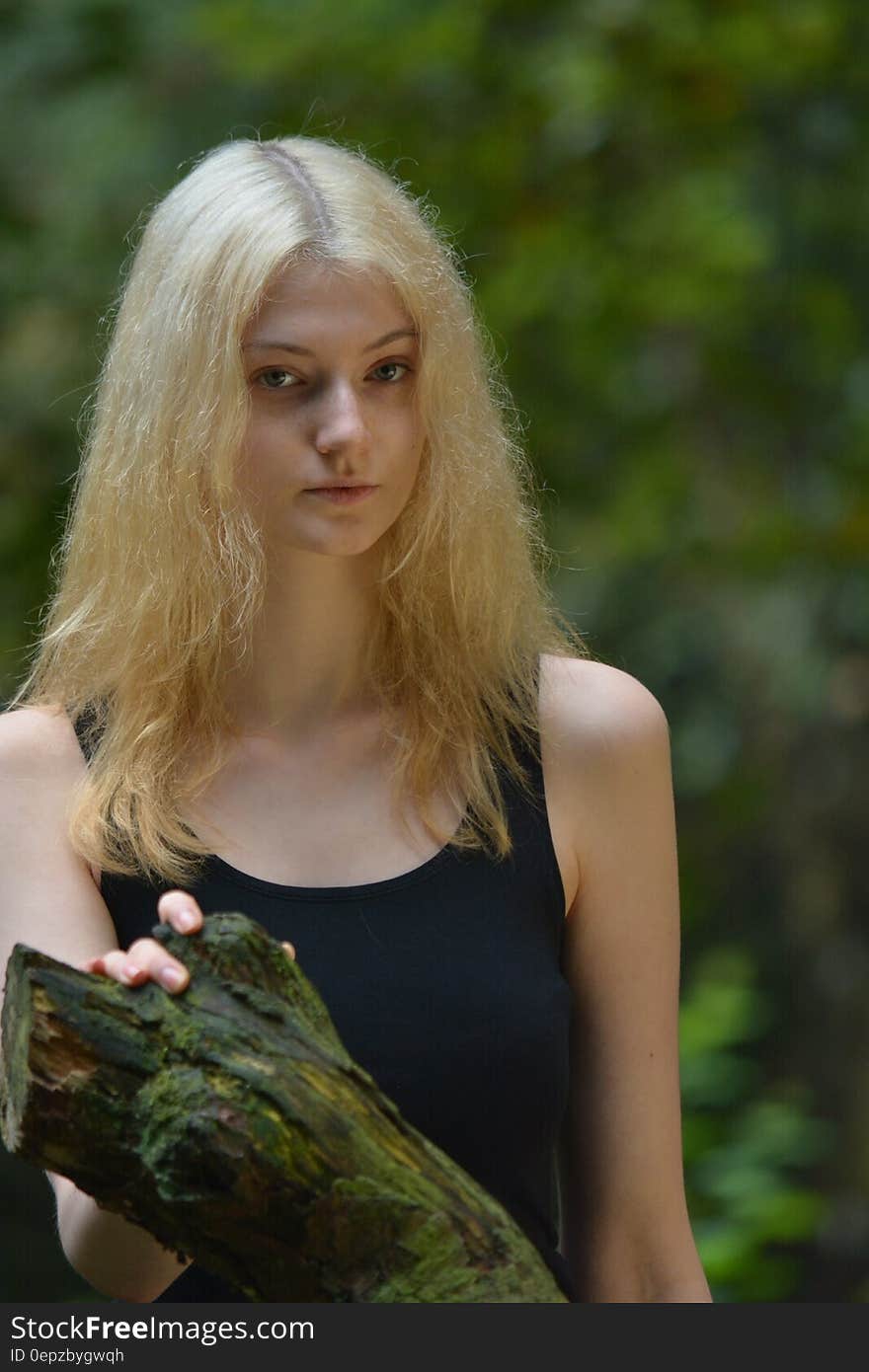 Woman in Black Tank Top While Her Right Hand Is Holding a Tree Branch