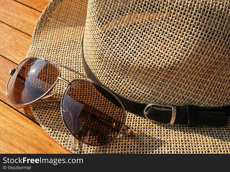 Brown Strawhat Beside Brown Aviator Sunglasses