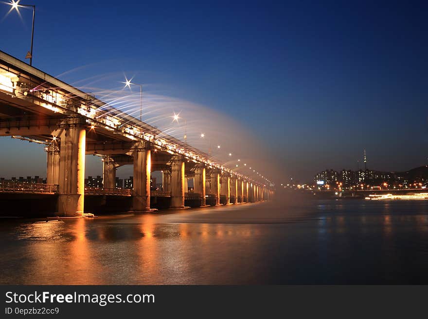 Streetlights illuminated on modern bridge with city skyline at night. Streetlights illuminated on modern bridge with city skyline at night.