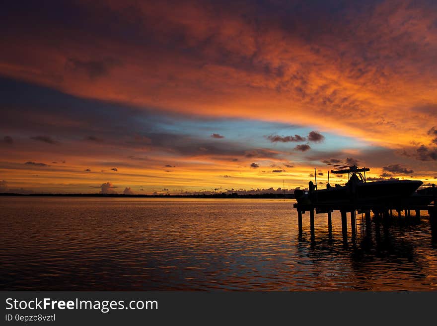 Silhouetted sea dock and colored sky reflecting on sea surface at sunset. Silhouetted sea dock and colored sky reflecting on sea surface at sunset.