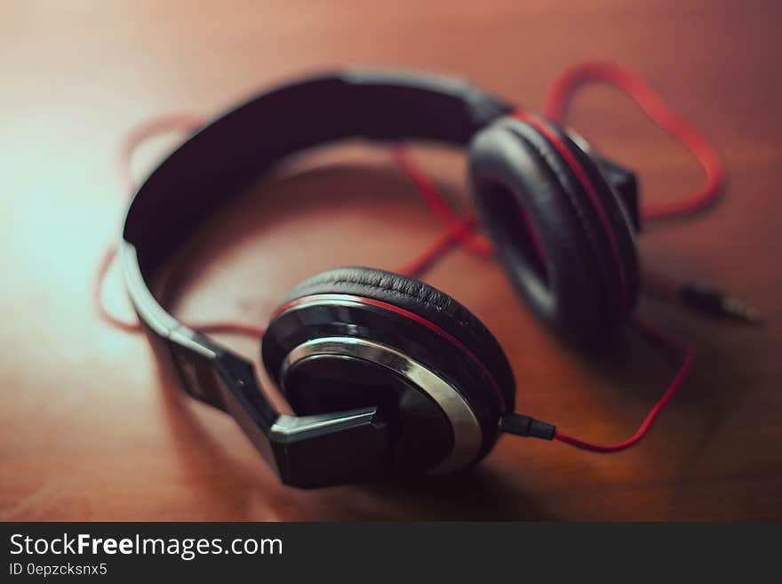 Closeup with selective focus of a pair of good quality audio headphones with headband and connecting wires visible.