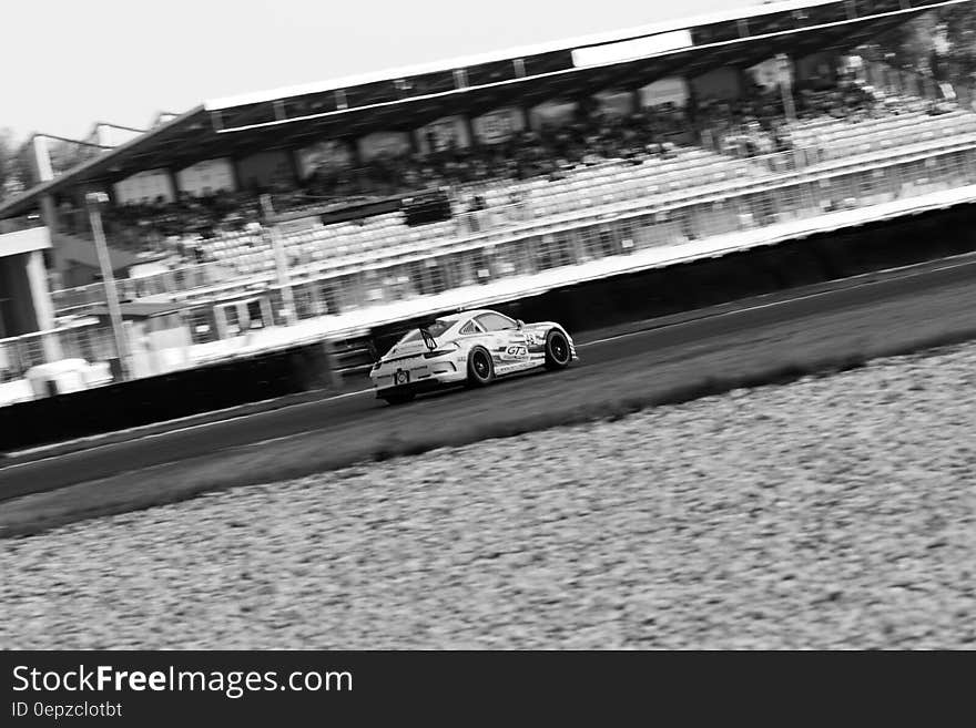 Production car tuned for speed with sponsors advertising on the sides taking part in a race and passing the stand with only a relatively few spectators watching. Production car tuned for speed with sponsors advertising on the sides taking part in a race and passing the stand with only a relatively few spectators watching.