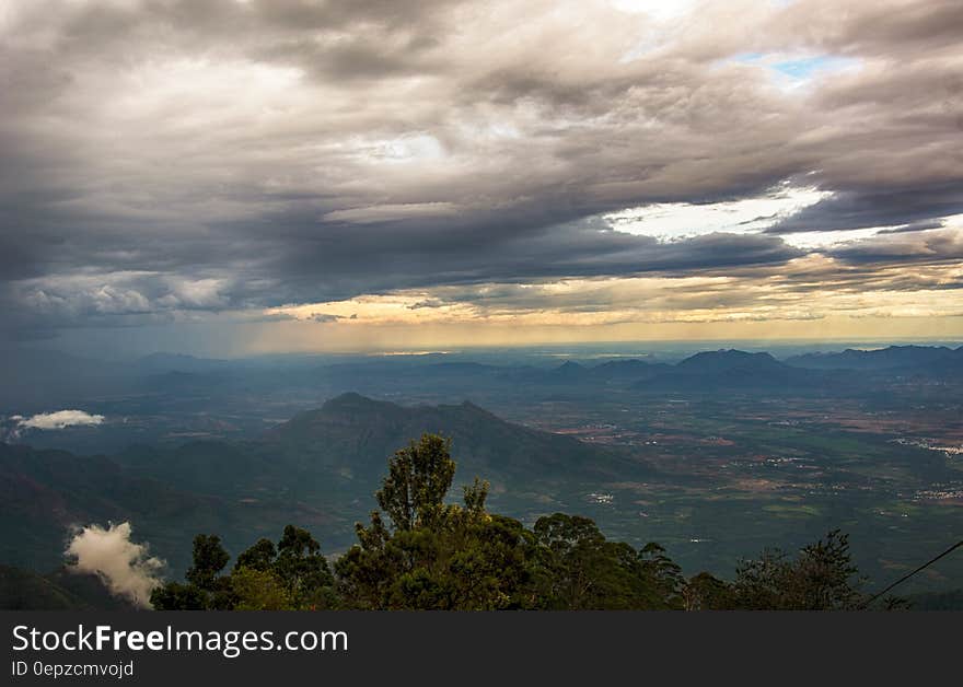 A scenic view from a mountain over valleys with cloudy skies above.