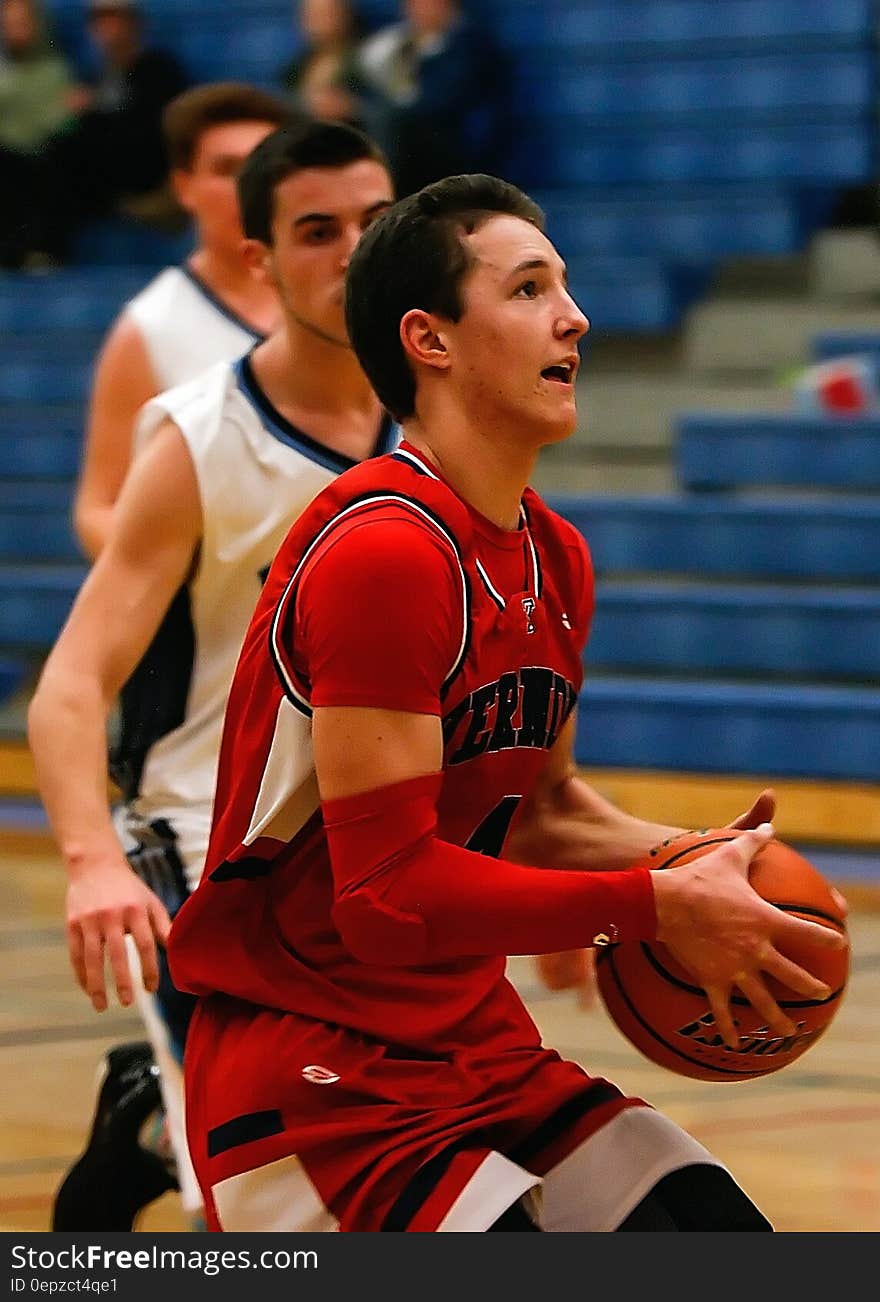 A Man Wearing Red Jersey Carrying an Orange Basketball