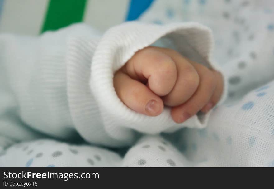 Close up on the hand of baby in white knit sleeve. Close up on the hand of baby in white knit sleeve.