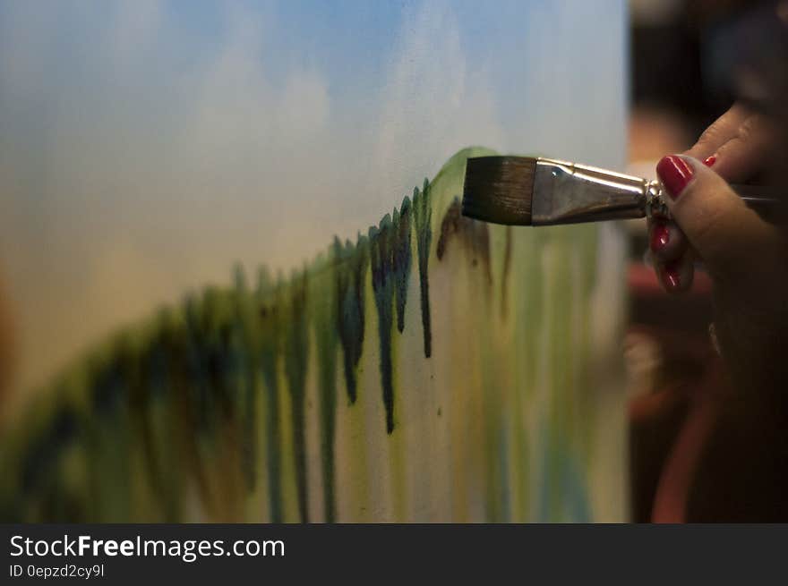 Woman With Red Nails Painting Green Stripe on Canvas