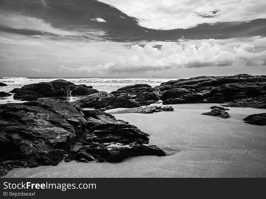 Grayscale Photography of Rocks on Seashore during Daytime