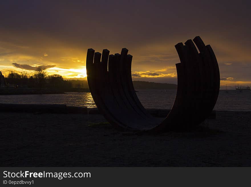 Silhouette Photo of Rock Monolith Nearby Ocean during Golden Hour