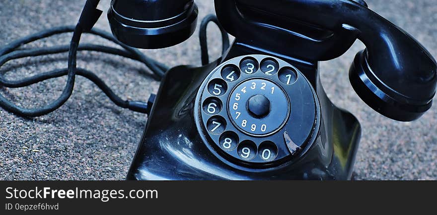 Black Rotary Telephone at Top of Gray Surface