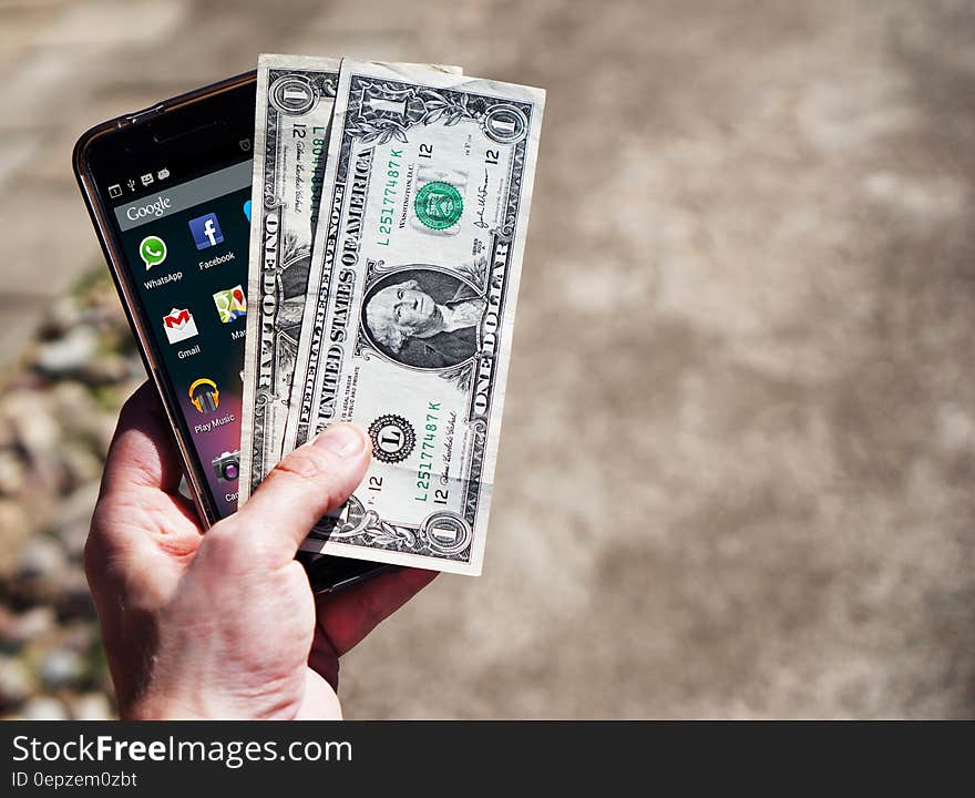 Persom Holding Black Android Smartphone and 2 1 U.s. Dollar