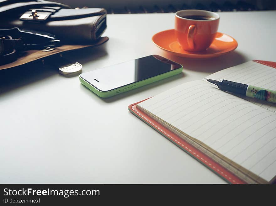 Green and Black Android Smartphone on Table Near Notebook