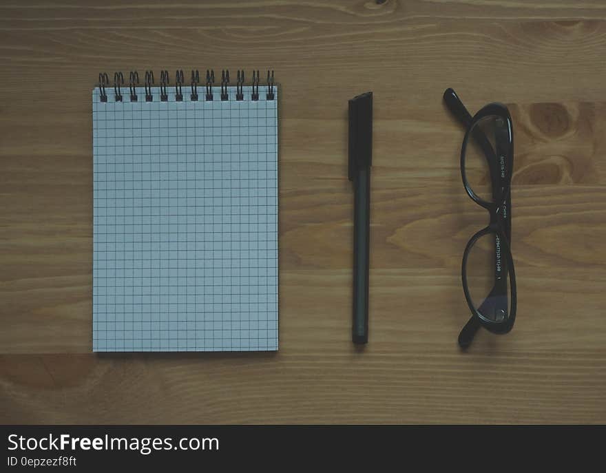 Black Framed Eyeglasses Near Graphing Paper Spiral Notebook