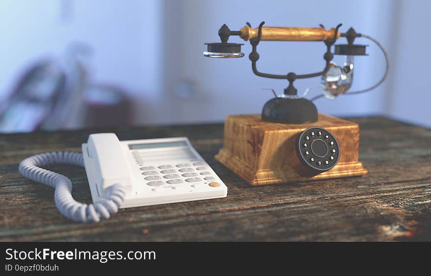 White Electric Home Phone Close to Rotary Phone on Table