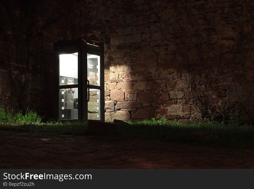 Telephone Booth Beside Brown Wall during Nighttime