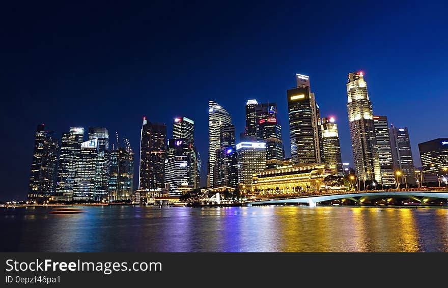 Waterfront skyline illuminated at night reflecting in waters. Waterfront skyline illuminated at night reflecting in waters.