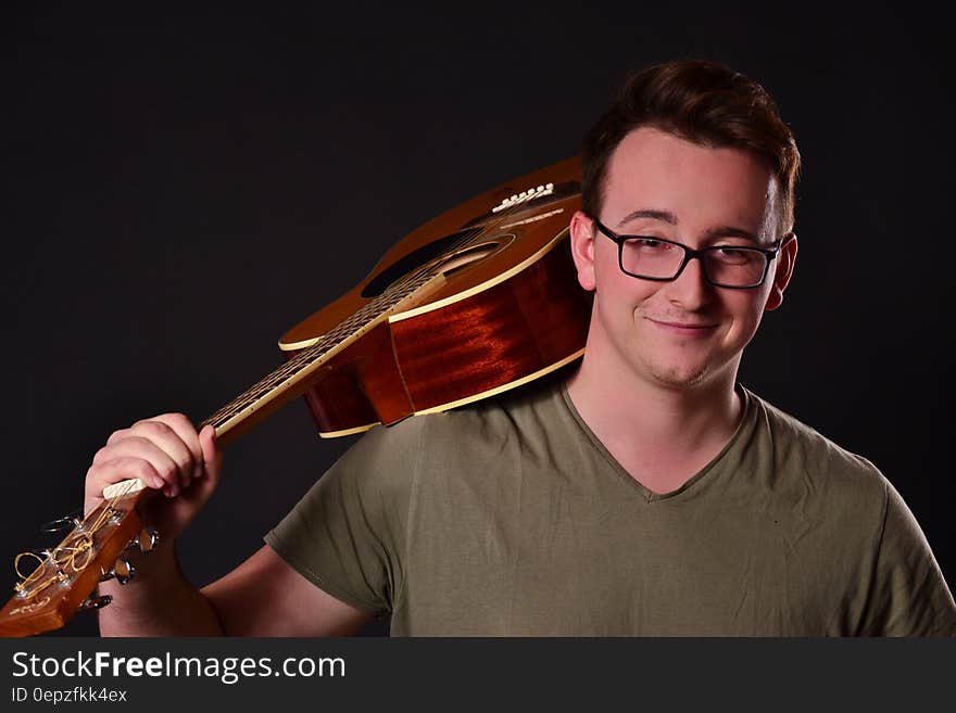 Man in Brown V Neck T Shirt Holding Acoustic Guitar