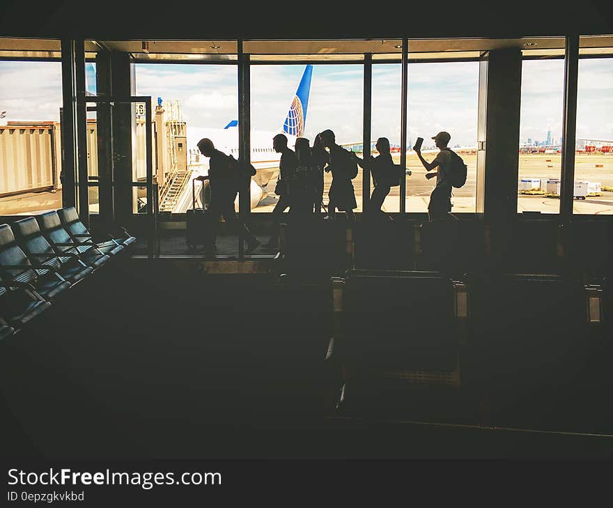 Group of People Walking Near Clear Glass Window With a View of White Airplane Parked during Daytime