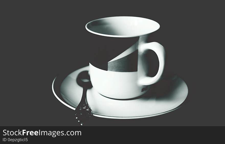 White and Black Ceramic Tea Mug on White Ceramic Round Plate and Stainless Steel Spoon on Top