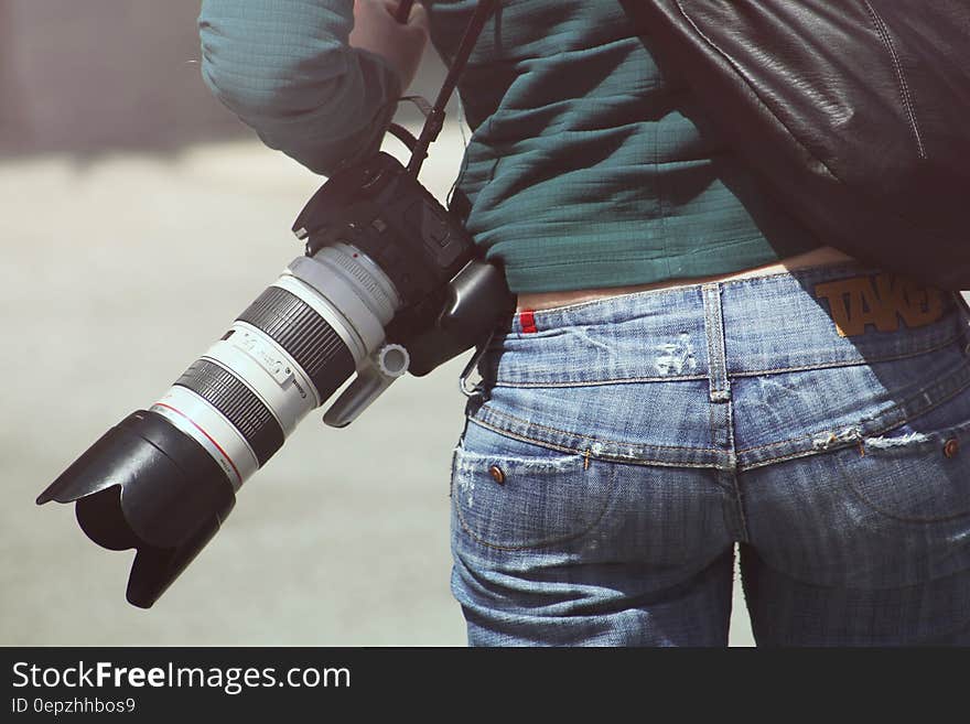 Photographer carrying camera with zoom lens on shoulder outdoors. Photographer carrying camera with zoom lens on shoulder outdoors.