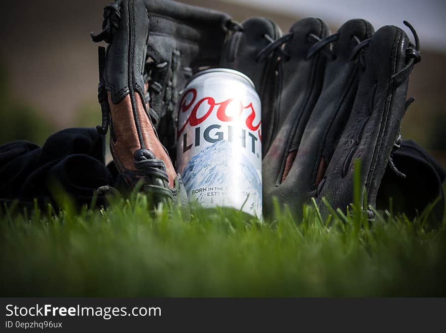 Close Up Photography of Coors Light Beer Near Black Baseball Mitts