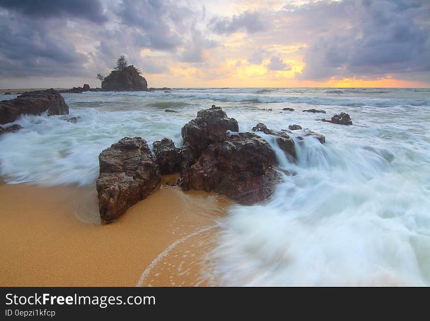 Rock on Beach Shore With Waves Crashing during Cloudy Daytime Sky