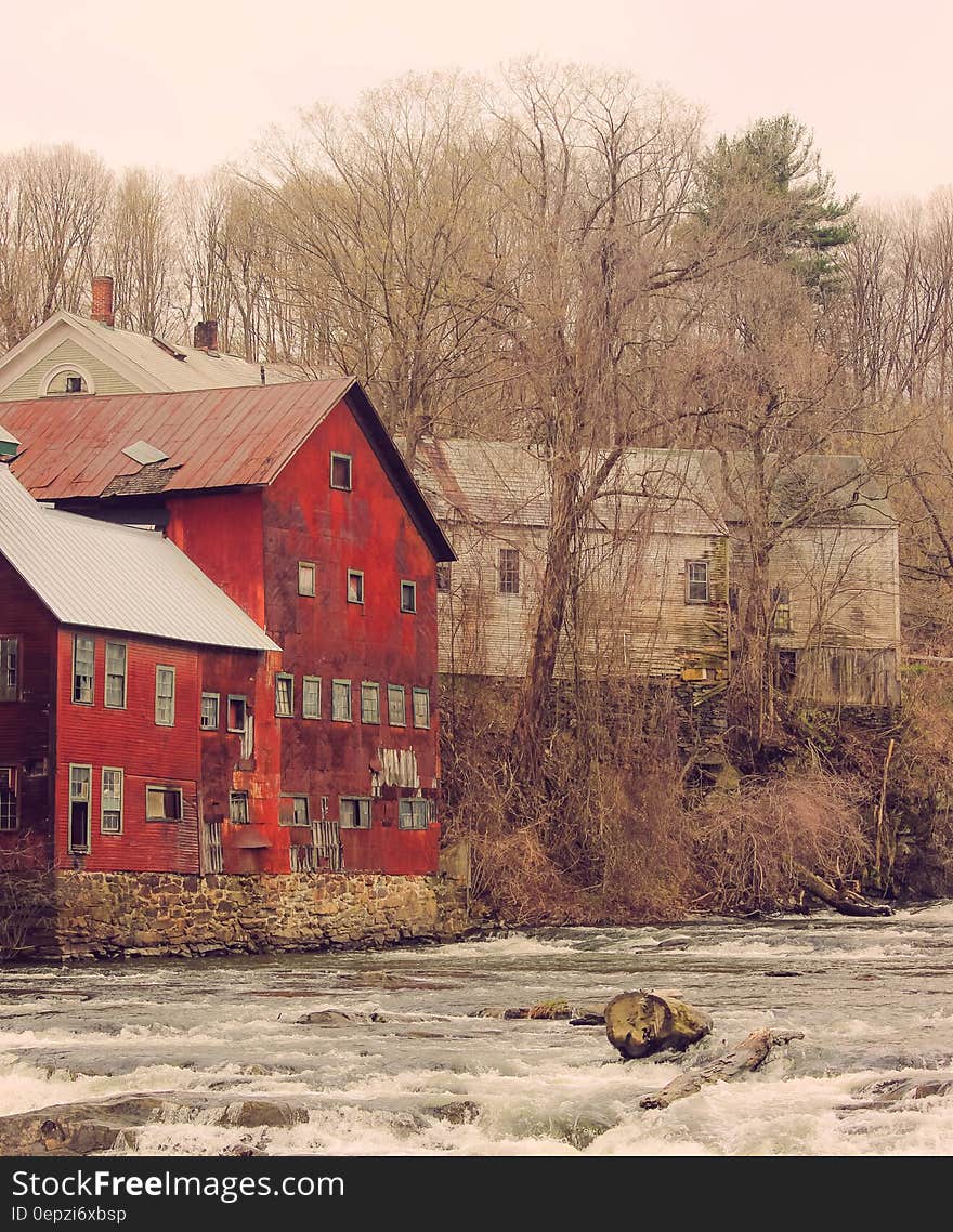 Red and Brown Concrete House Near to White and Gray Wooden House during Daytime