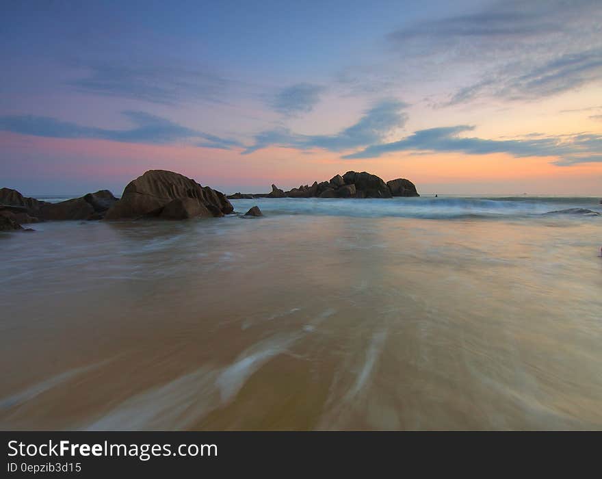 Sunset over rocks along sandy beach. Sunset over rocks along sandy beach.