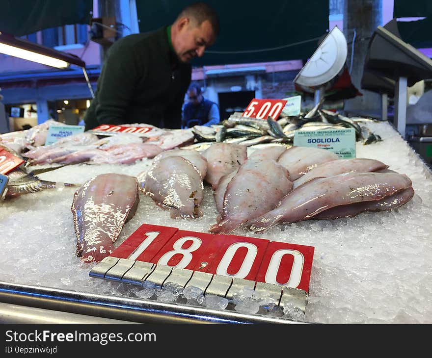 Man working at fish market with fresh catch on ice. Man working at fish market with fresh catch on ice.