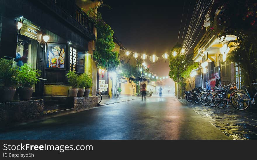 Person Standing on Gray Path Way Near Bicycles during Night Time