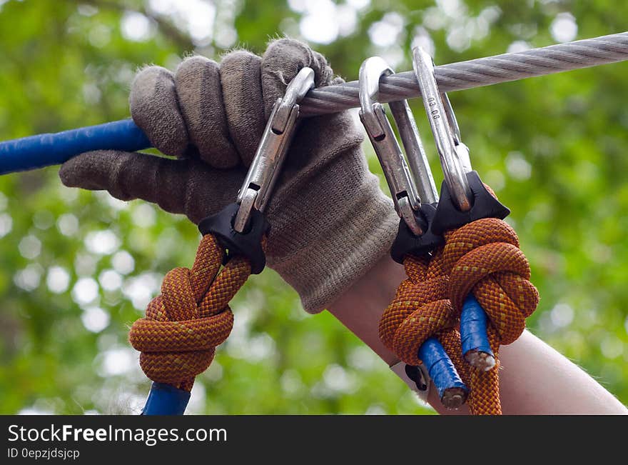 Person in Gray and Beige Gloves Holding on Gray Cable Wire