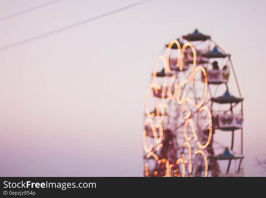 Blur of lights and motion on Ferris Wheel at sunset.