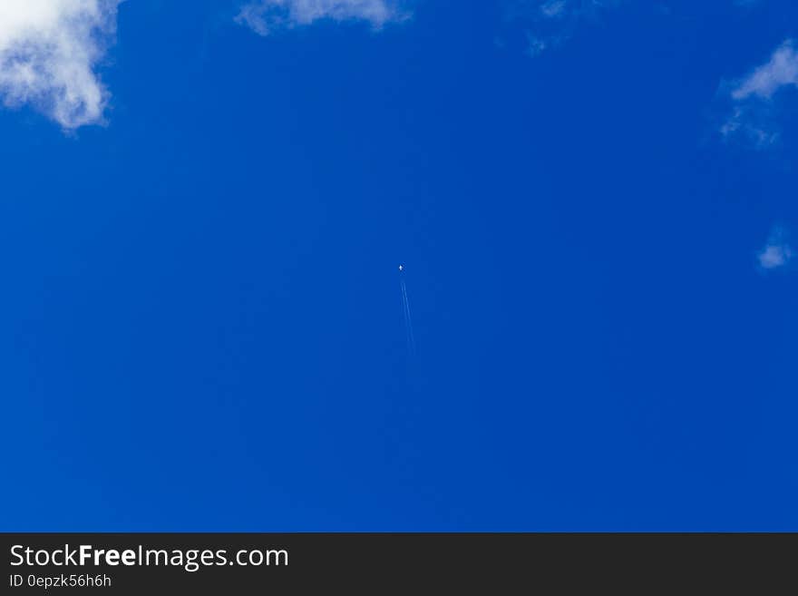 Distant aircraft flying in blue sky with cloudscape.