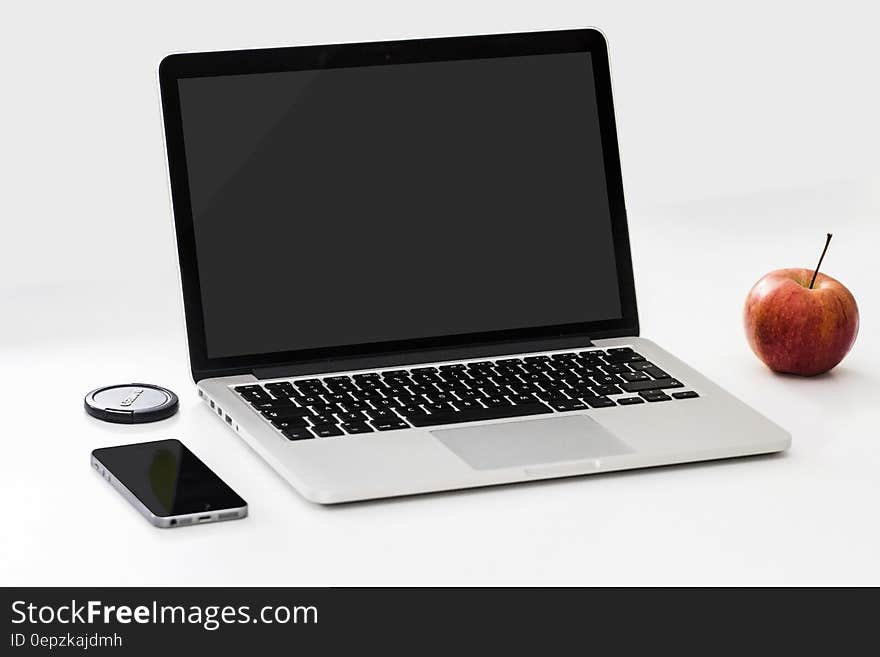 Open Macbook next to ripe apple and smartphone, white background. Open Macbook next to ripe apple and smartphone, white background.