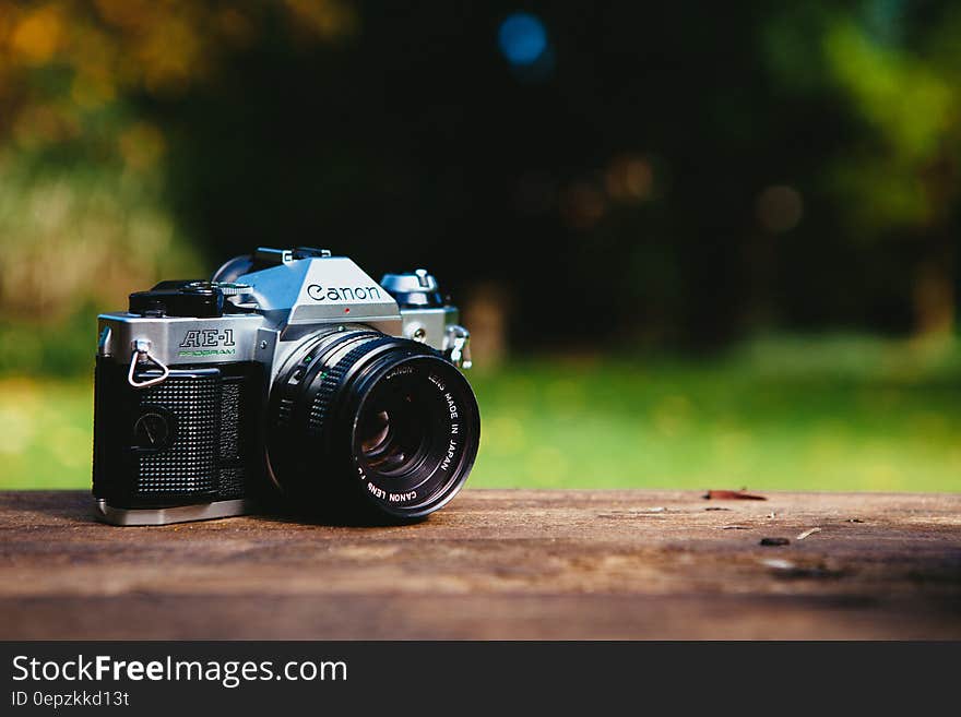 Close up of vintage Canon AE-1 analog film camera on wooden rail outdoors. Close up of vintage Canon AE-1 analog film camera on wooden rail outdoors.