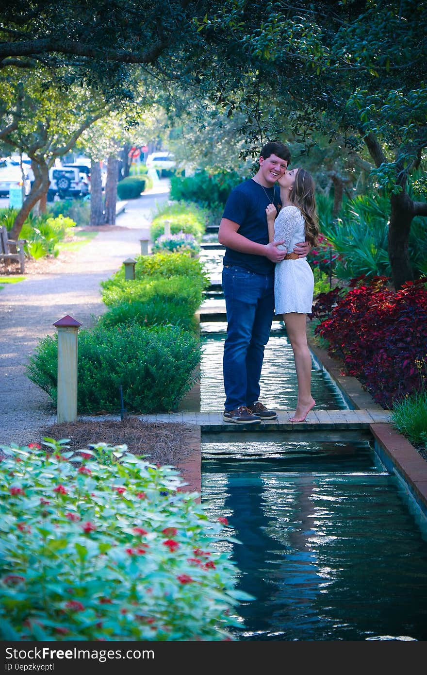 Woman and Man Standing on Bridge Kissing