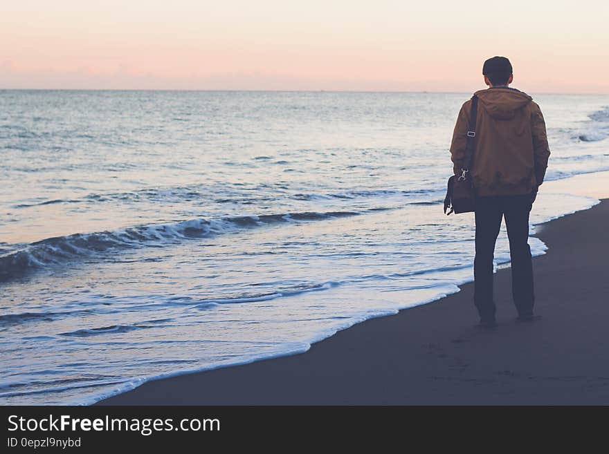 A man standing on beach watching the sea.