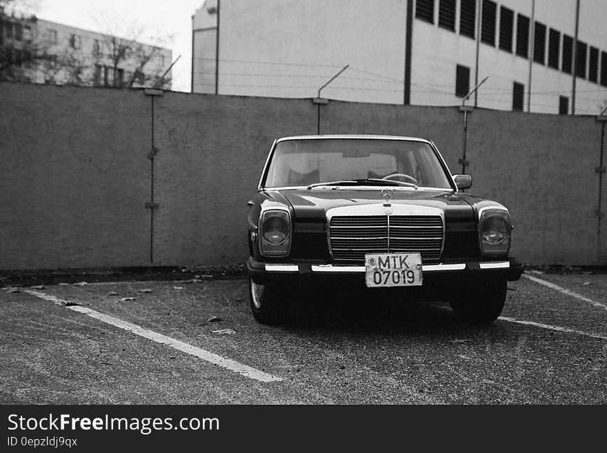 Monochrome view of German Mercedes Benz car parked next to wall with security wire.