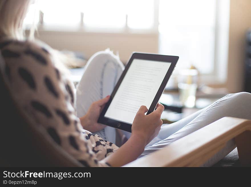 Woman Sitting on Chair Using Black Ipad