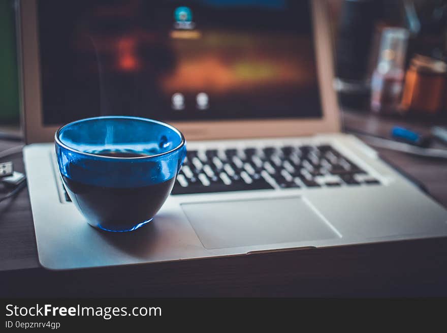 Blue Glass Cup on Silver Laptop Computer