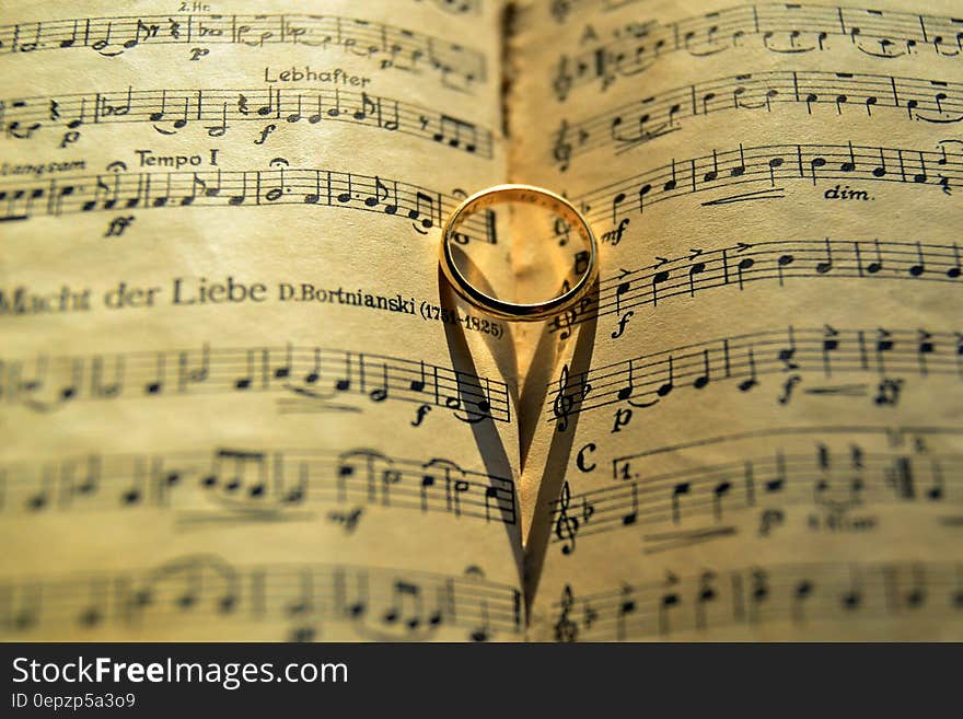 Close up of gold band on open sheets of music score. Close up of gold band on open sheets of music score.