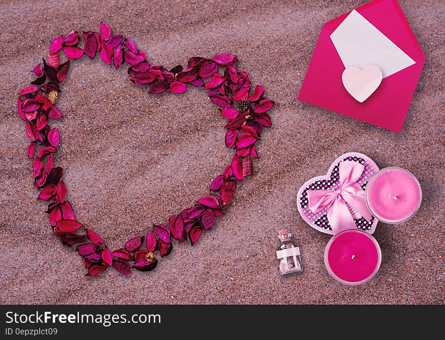 Valentine's Day still life of flower petals in heart shape with card and candles on sand. Valentine's Day still life of flower petals in heart shape with card and candles on sand.