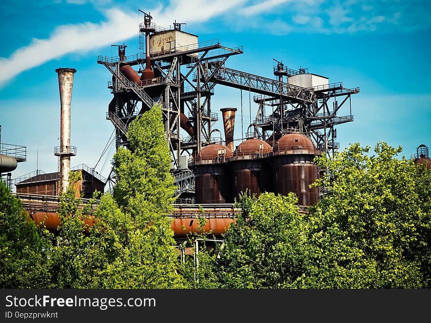 An old industrial building behind green trees.