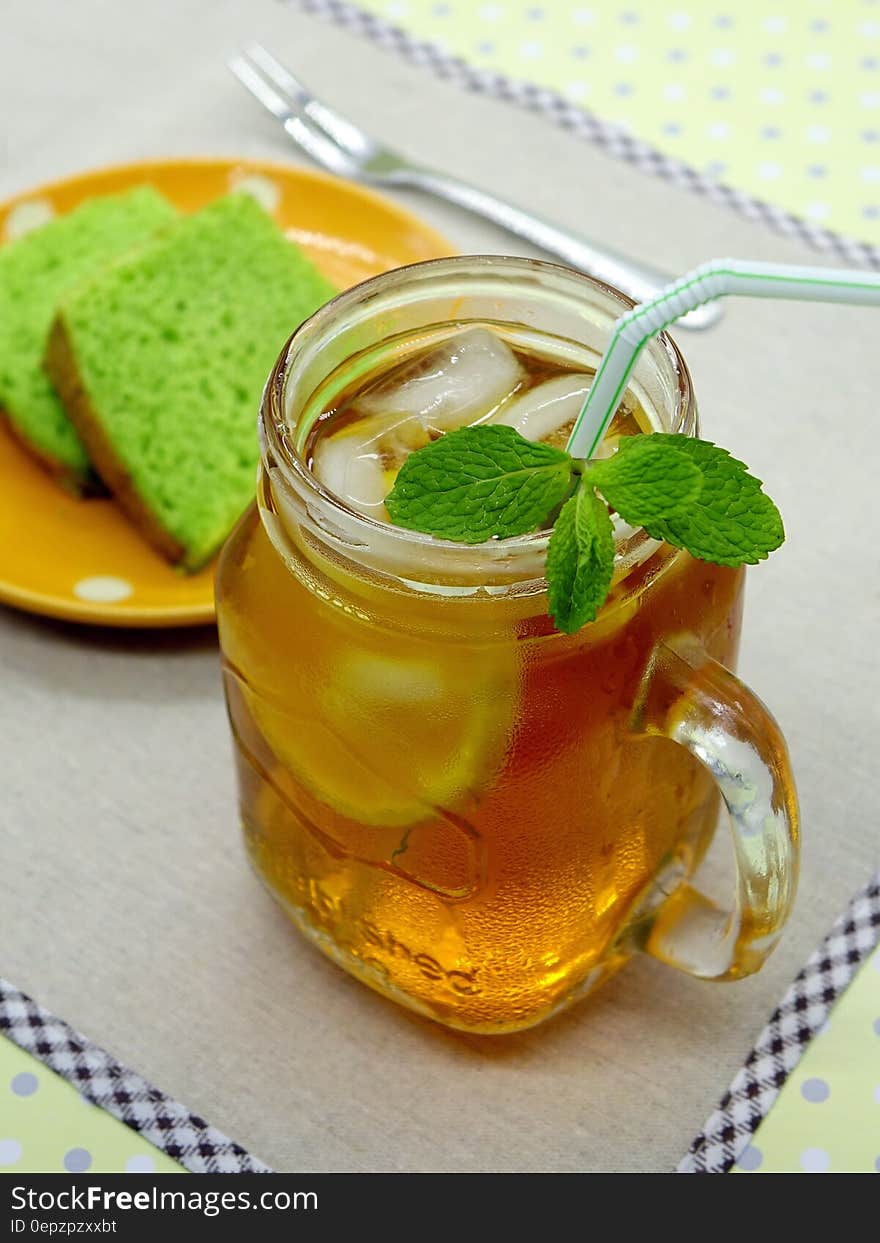 Iced tea with mint in mason jar on table with plate of green cakes.